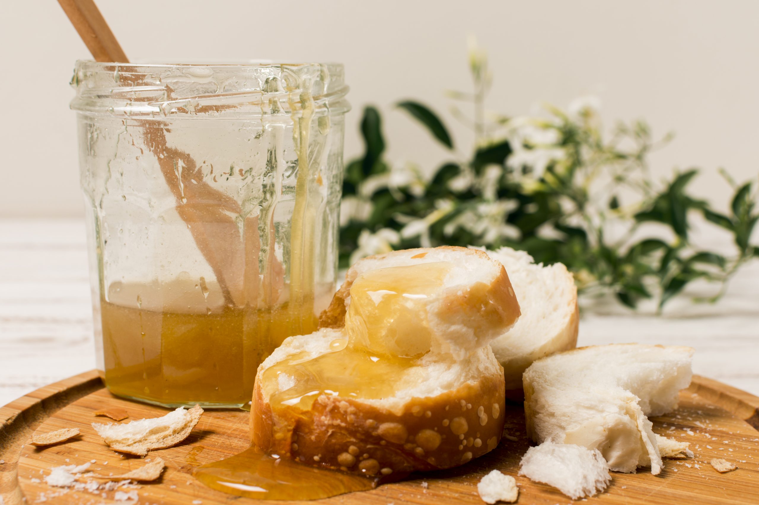 Vegane Alternativen zu Honig Brot auf einem Holzbrett mit Honig beschmiert und einem Honigglas daneben